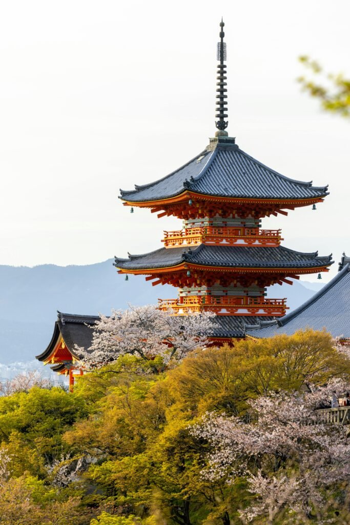 Kiyomizu-dera Temple in Kyoto with cherry blossoms, orange roofs, and green trees