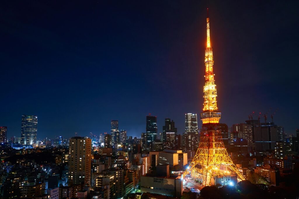 Tokyo Tower lit up at night, standing tall among city buildings against a dark sky.