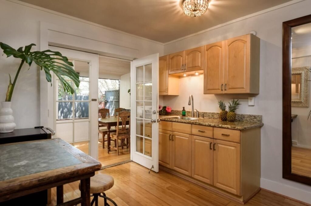 Paia Inn-Cozy kitchenette with wooden cabinets and open door to dining area.